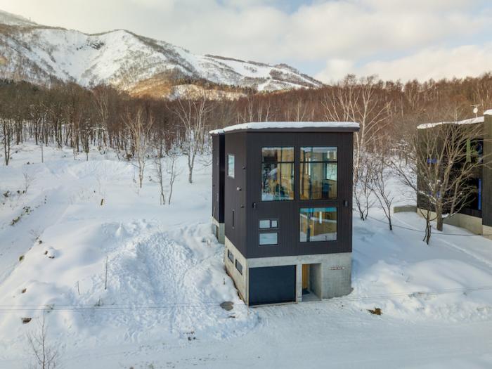 A two story house with large windows surrounded by snow