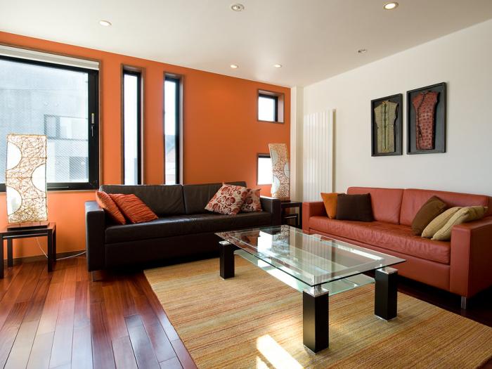 Living area with glass coffee table red and black leather sofa and wall art