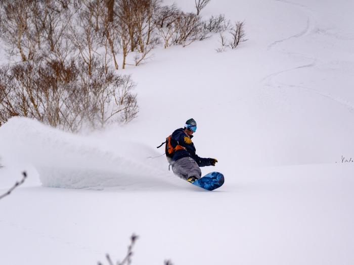 A snowboarder makes a deep turn in the powder