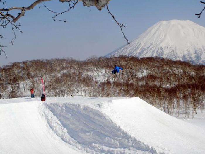 A snowbaorder jumping with Mount Yotei in the background