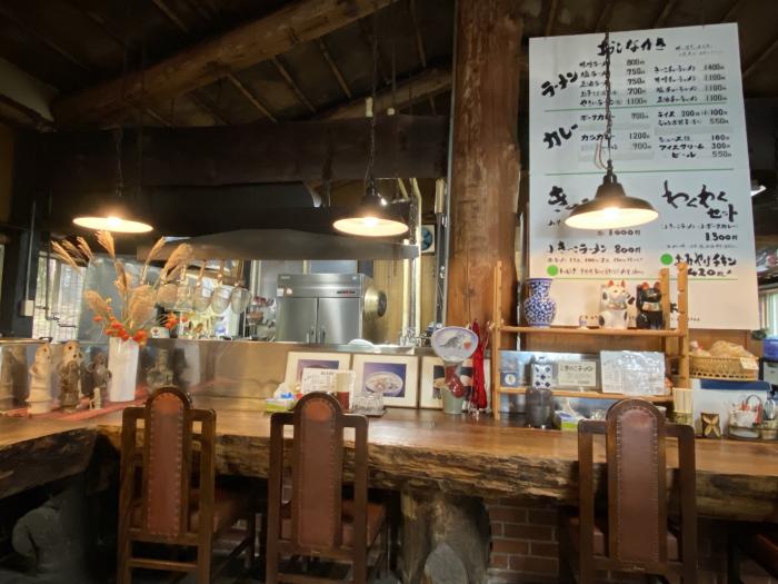 A ramen shop counter in a log cabin with 3 hanging lights and a live edge wooden counter