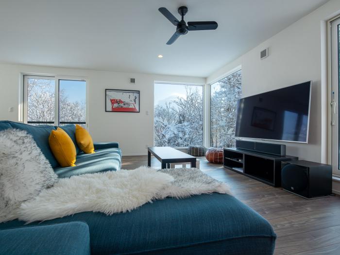 A blue couch with TV to the right and windows behind