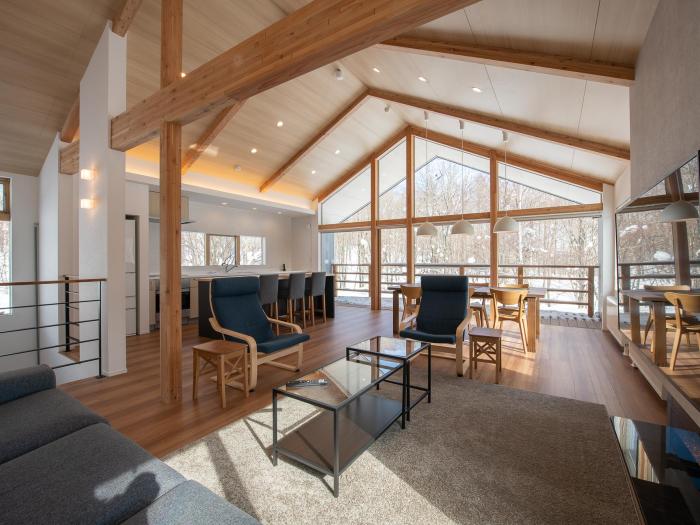 The Hikaru living room with high A frame ceiling, coffee table and large windows at the end.