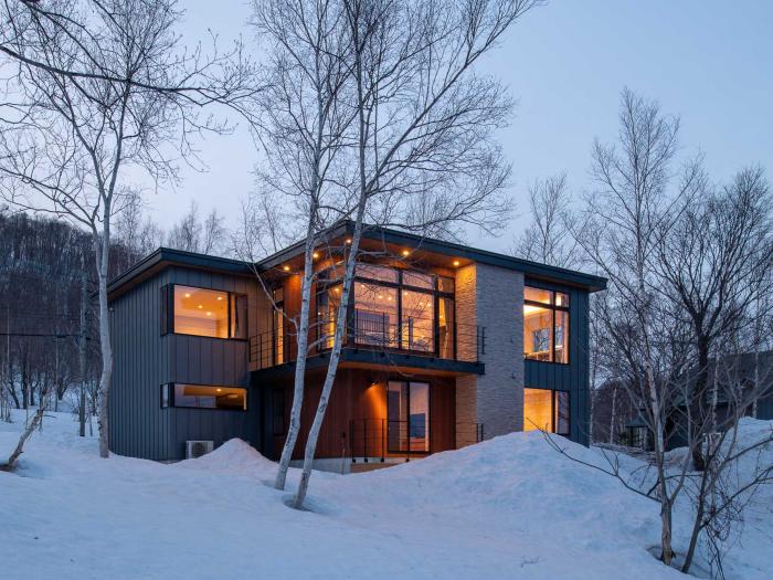 A 2 story home at dusk with lights on.