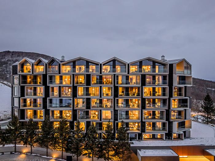 The exterior of a six story hotel in the snow with lights on