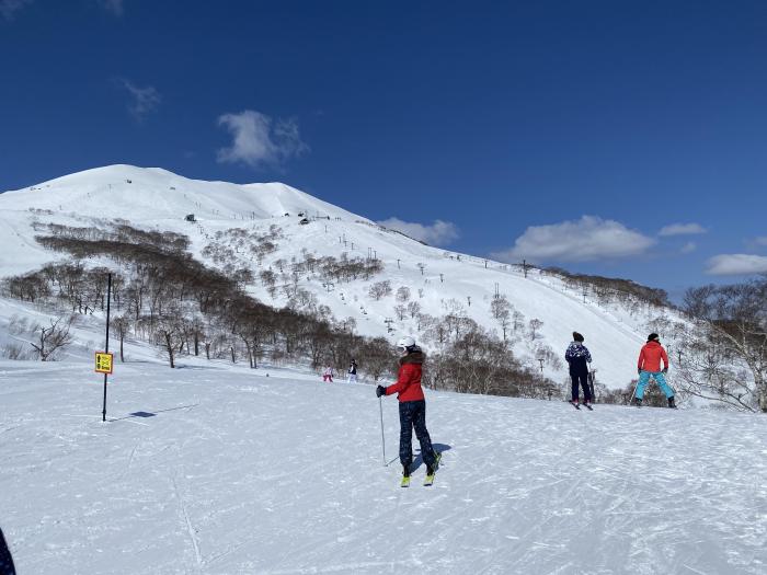 3 skiers on a flat area with mountain above