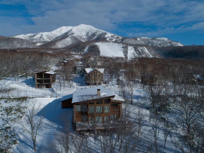 Chalet Kiraku in Niseko, featuring contemporary Japanese design with spacious living areas, 8 bedrooms, private jacuzzi, and ski facilities. Luxury mountain accommodation with stunning views.