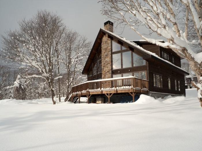 Luxury wooden ski chalet in Niseko surrounded by fresh powder snow and winter trees, perfect for family ski holidays.