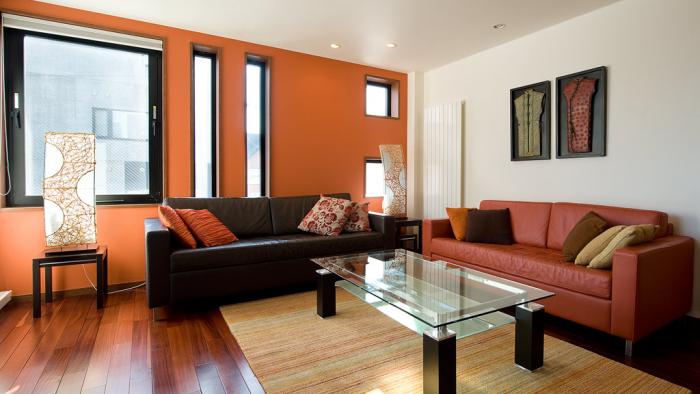 Living area with glass coffee table red and black leather sofa and wall art