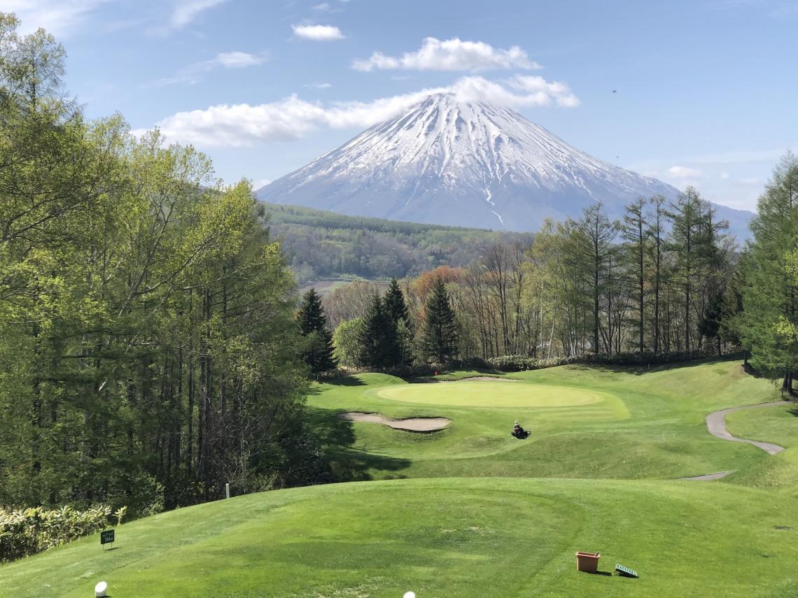 The greens of a golf course with Mount Yotei in the back ground
