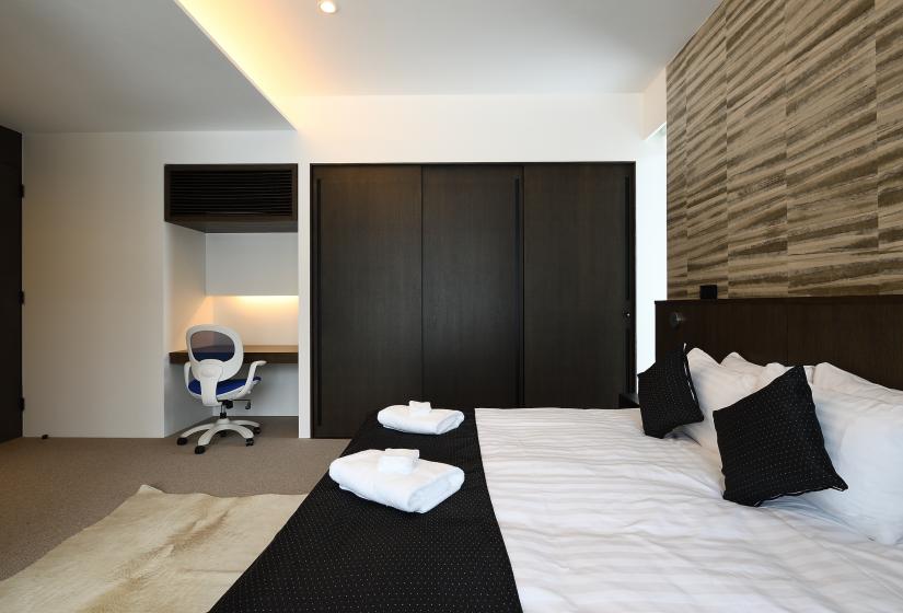 large bed with black closet doors and small desk with chair