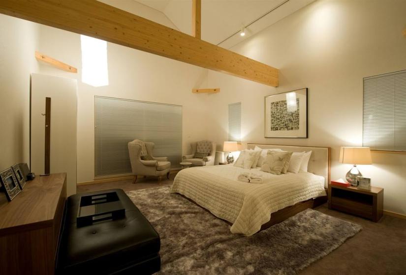 master bedroom with couches lounge chairs and exposed wooden beam