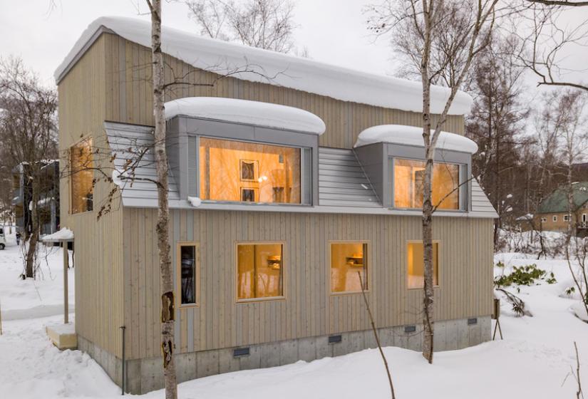 A two story building with lights on and snow on roof