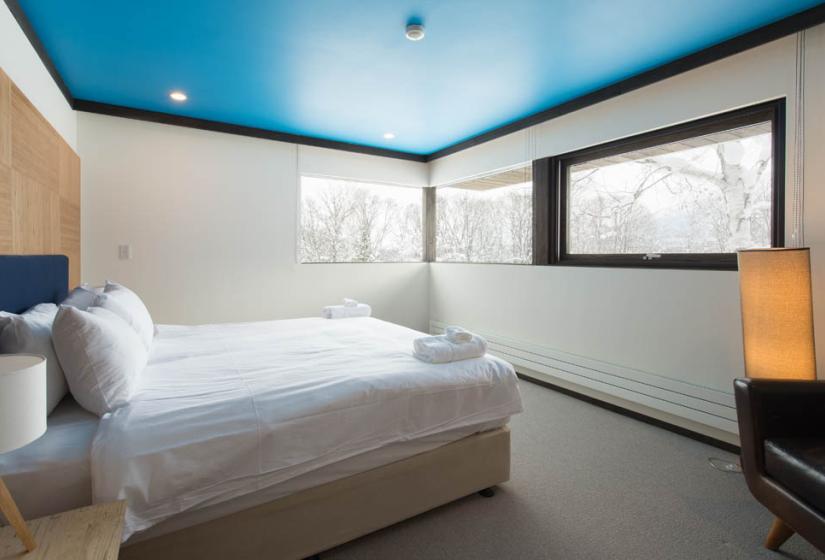 large bed with blue ceiling and windows