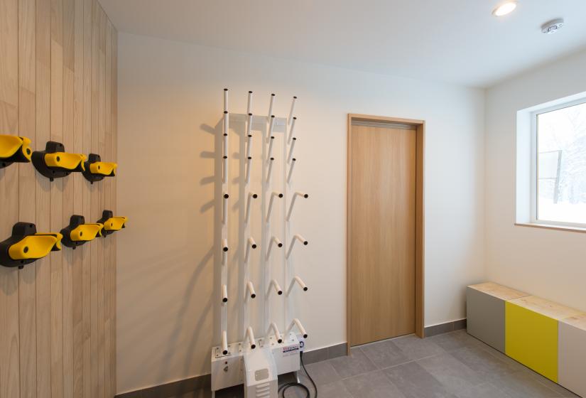 Ski drying rack on white wall with wooden door