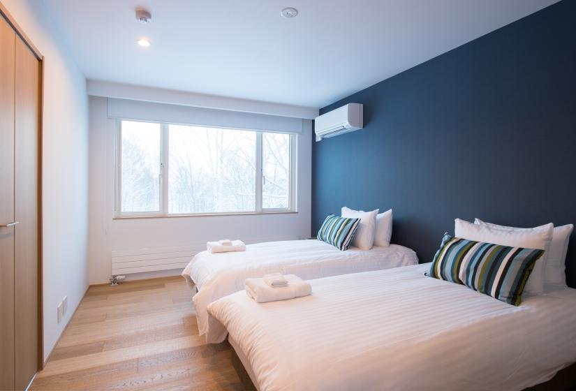 twin beds with white sheets blue wall and window