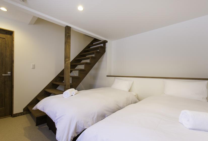 stairs leading down to bedroom with 2 single beds