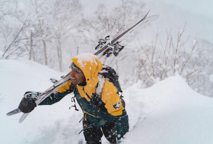 A skiier treks up a snow slope