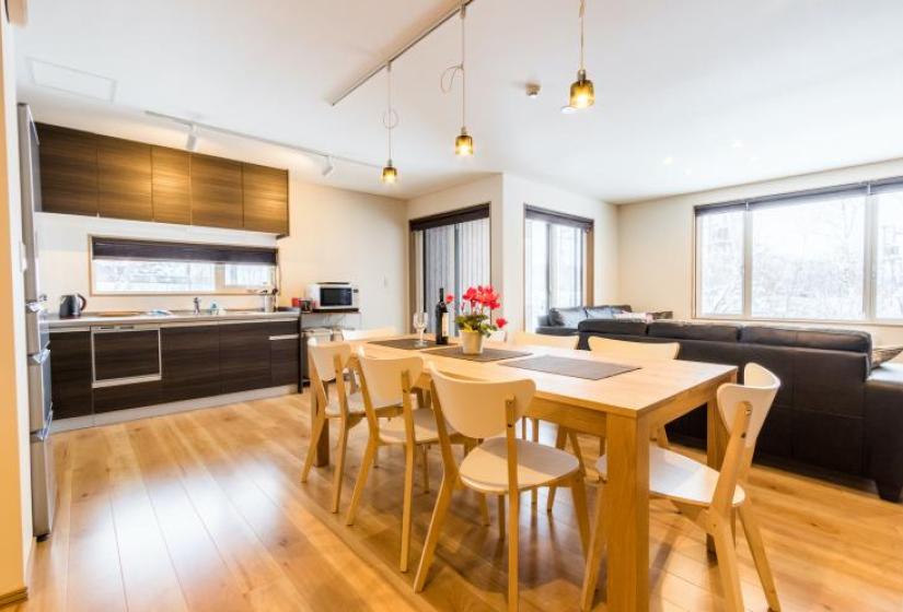 Kitchen and dining area A dining table and kitchen behind with hanging pendant lights