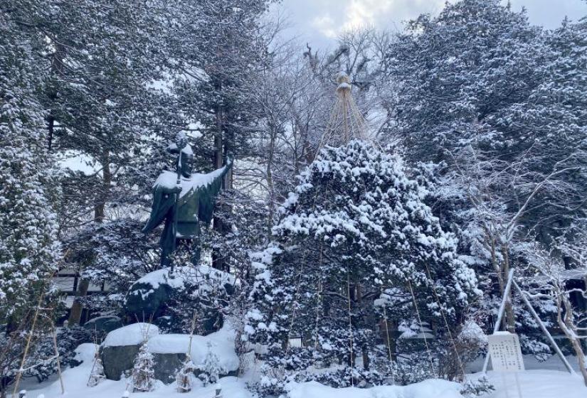 A large statue surrounded by snowy trees