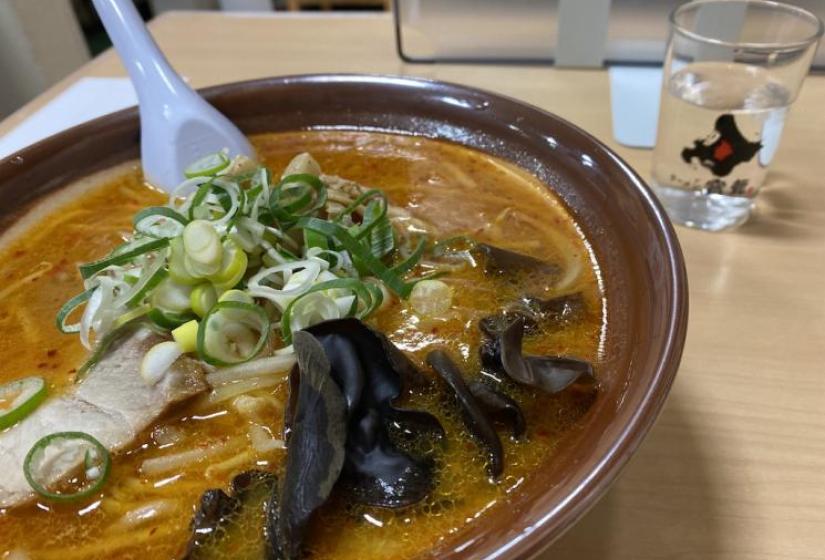 Sapporo Ramen A bowl of noodles in a red soup with fresh cut spring onions