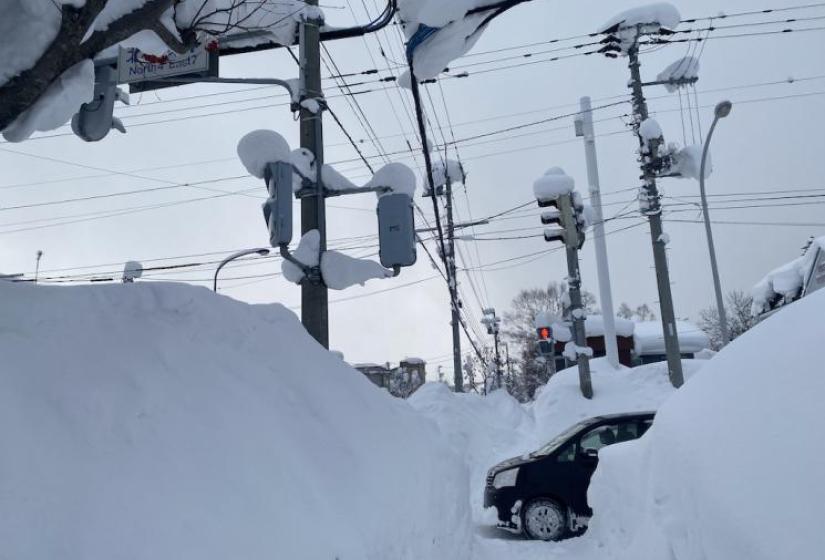 A snowy tunnel like foot path with a car at the crossing