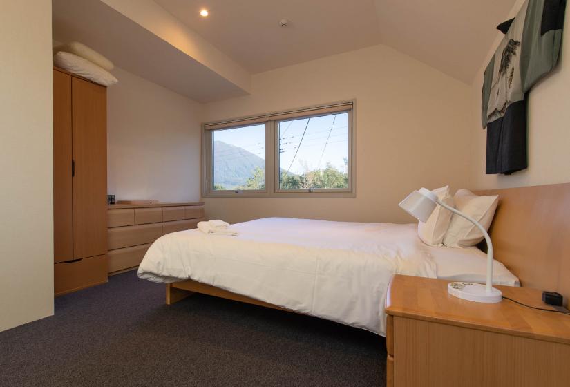 double bed on brown carpet with view of mt Yotei