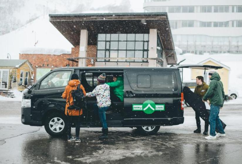 Seamless transfer service Ski luggage is loaded into a black van on a snowy day