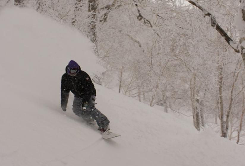 A snowboarder makes a deep turn in the powder