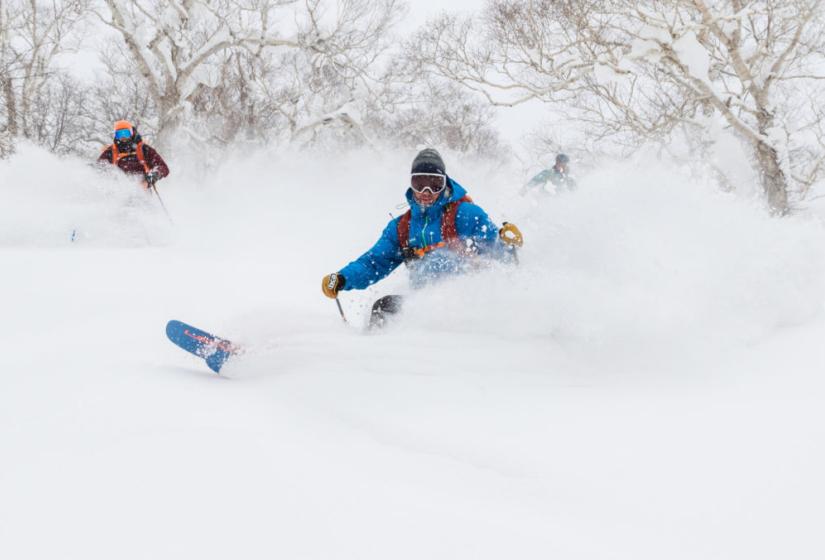A skier makes a deep turn in powder snow.