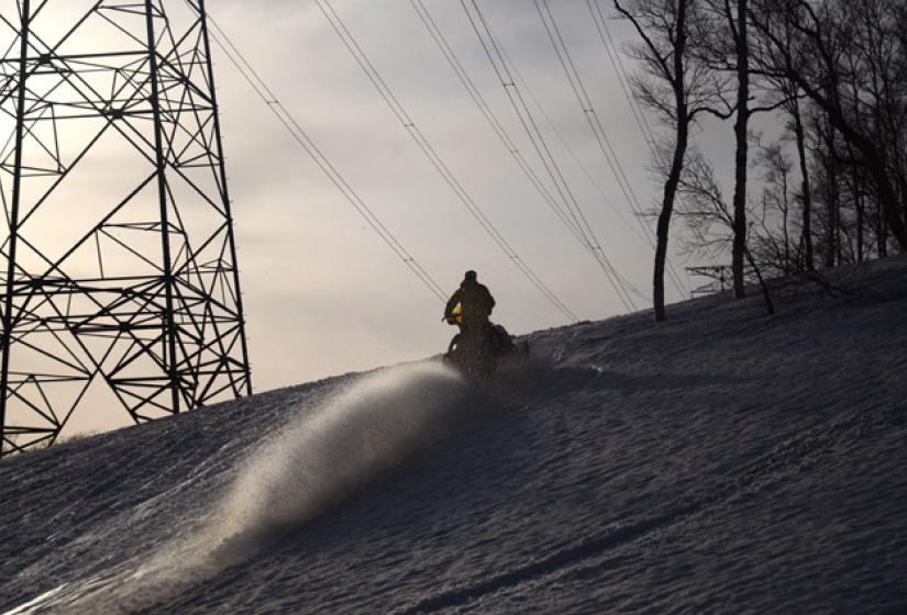 A snowmobile below large power pylons.