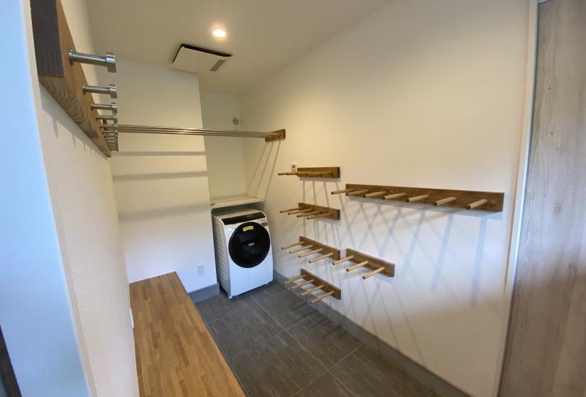 a washing machine in the corner of a small room with ski racks on the walls