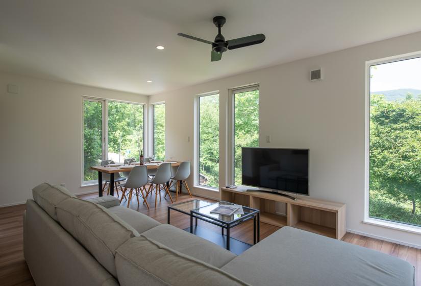 A lounge suite with TV, coffee table and dining table behind.