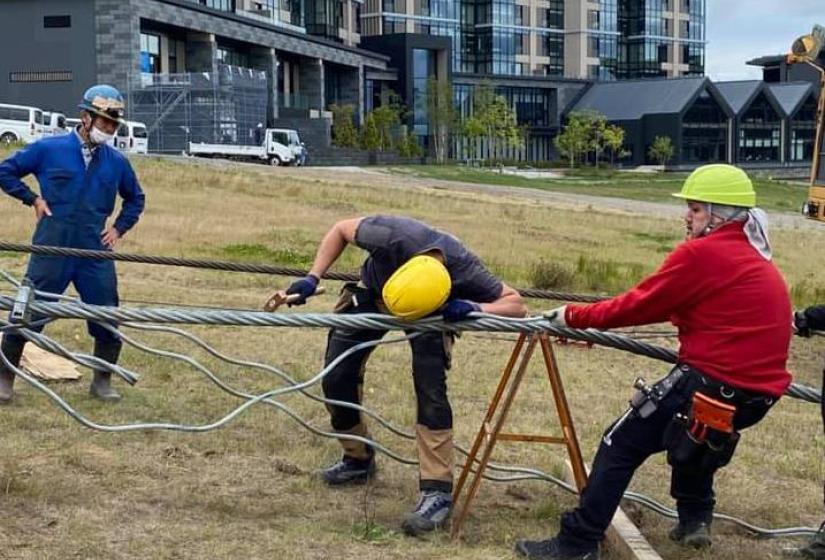 Men in yellow helmets splice a chairlift cable