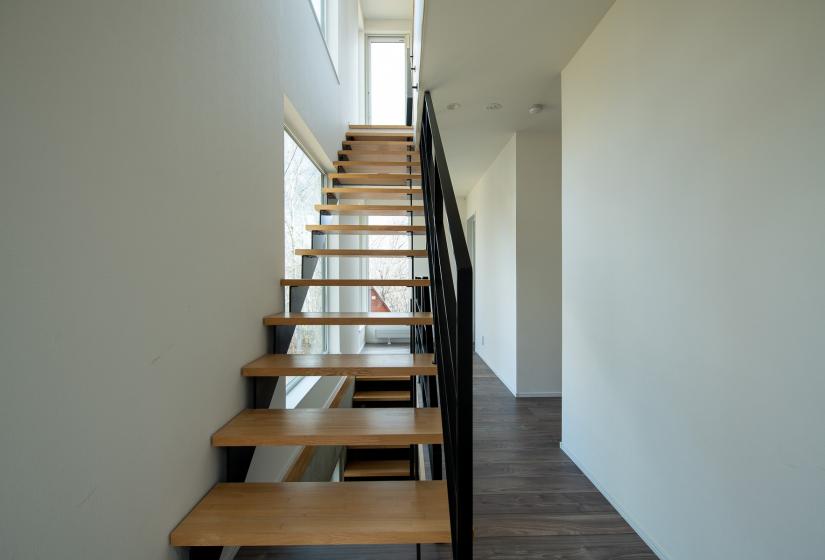 A stair case with black handrails and white wall to the left.