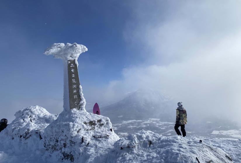 A snow crusted monument at the top of Mount Annupuri with Mount Yotei in the back ground.