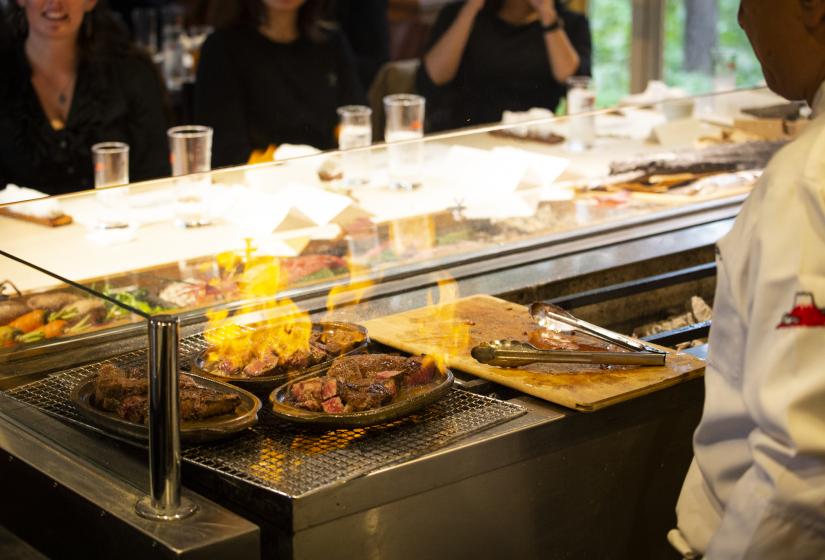 A chef works behind a grill with flames