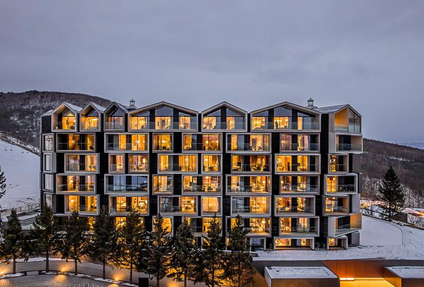 The exterior of a six story hotel in the snow with lights on