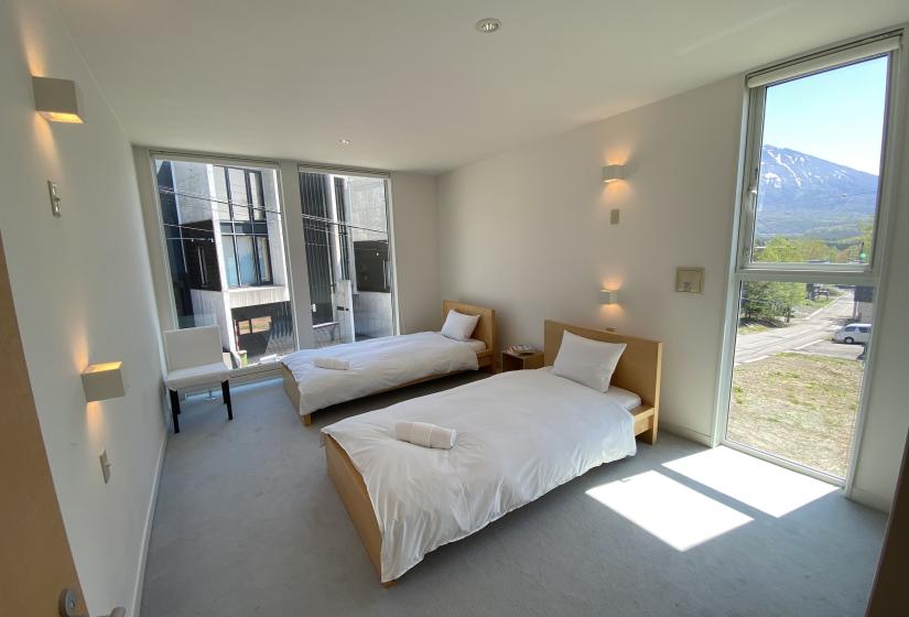 Two made up double beds with window to the right