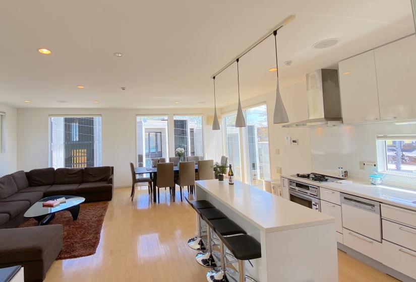A white kitchen bench with lounge behind