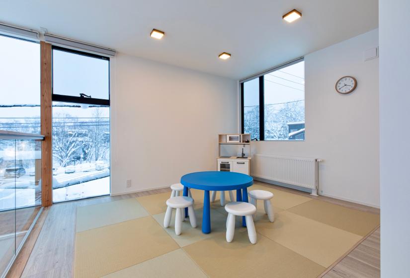 A tatami room with a blue table and white chairs