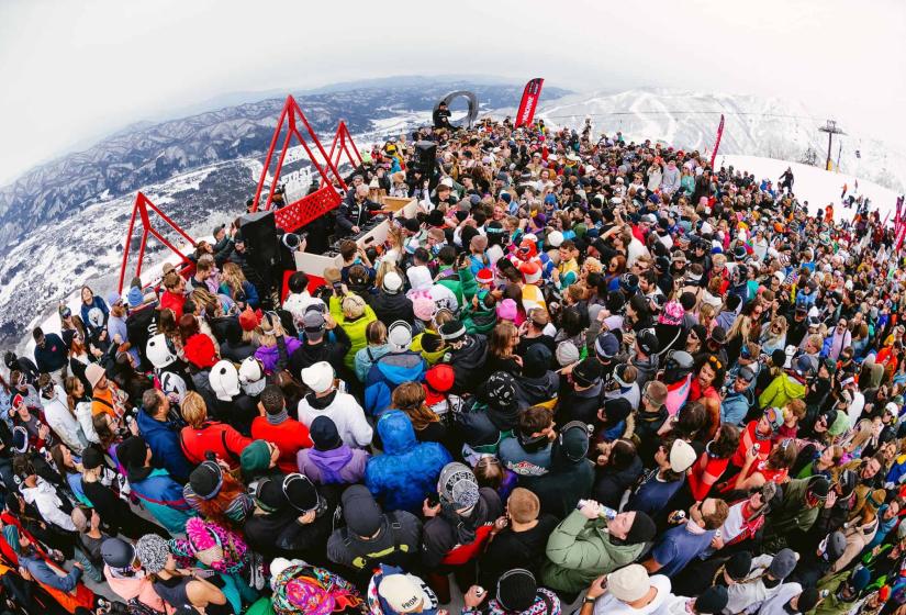 A crowd of festival goers with snow Japanese hills and chairlift behind