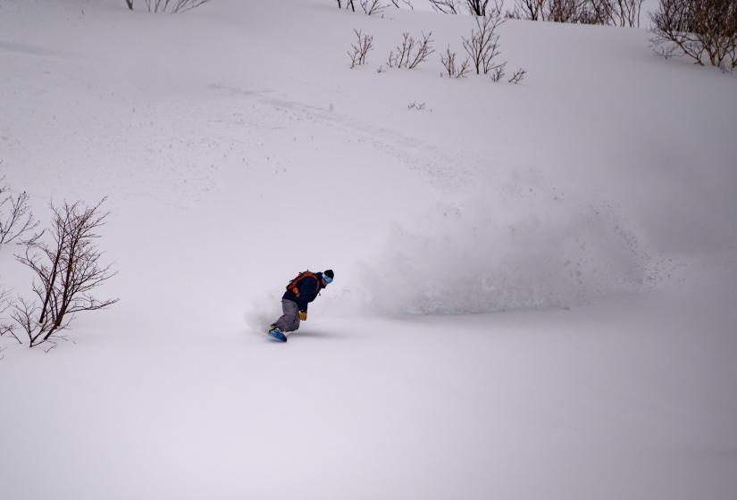 A snowboarder makes a turn in the powder