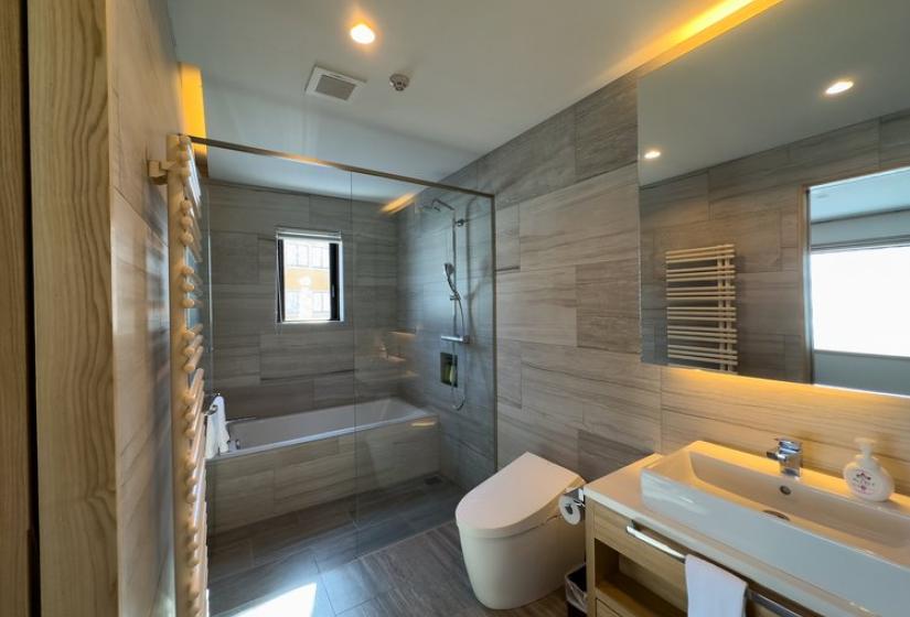 Modern ensuite bathroom with grey stone tiles, walk-in shower, heated towel rail, and vanity with integrated lighting