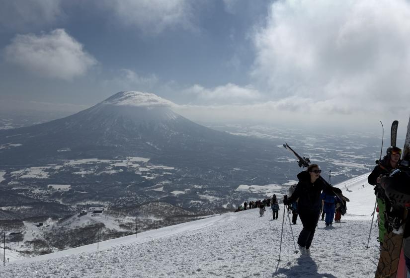 An incredible March day on the Annupuri peak. Skiers hike up a slope with Mount Yotei in the background