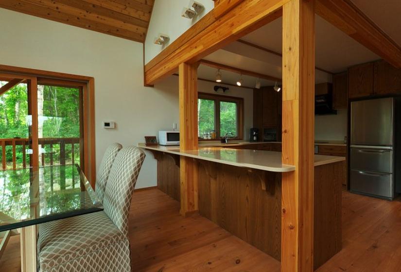 Spacious Niseko ski chalet interior with wooden beams, open plan kitchen, and large windows overlooking Annupuri ski resort, showcasing premium ski accommodation in Hokkaido, Japan