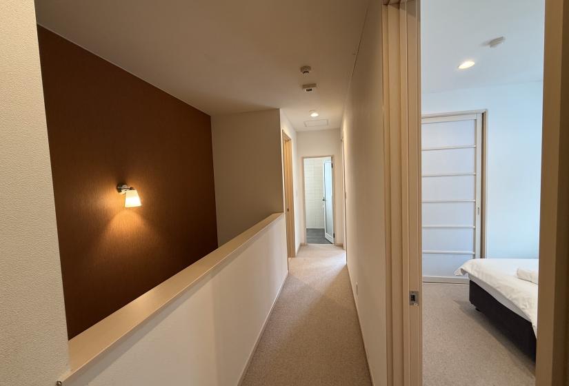 Modern hallway at Yutaka Townhouses featuring warm wood accent wall, bright lighting, and access to premium bedrooms ideal for Niseko ski holiday accommodations.