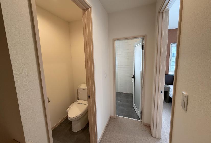 Clean hallway entrance to bathroom and bedroom areas at Yutaka Townhouses featuring minimalist design, bright lighting, and contemporary doors providing access to ensuite facilities and sleeping quarters.