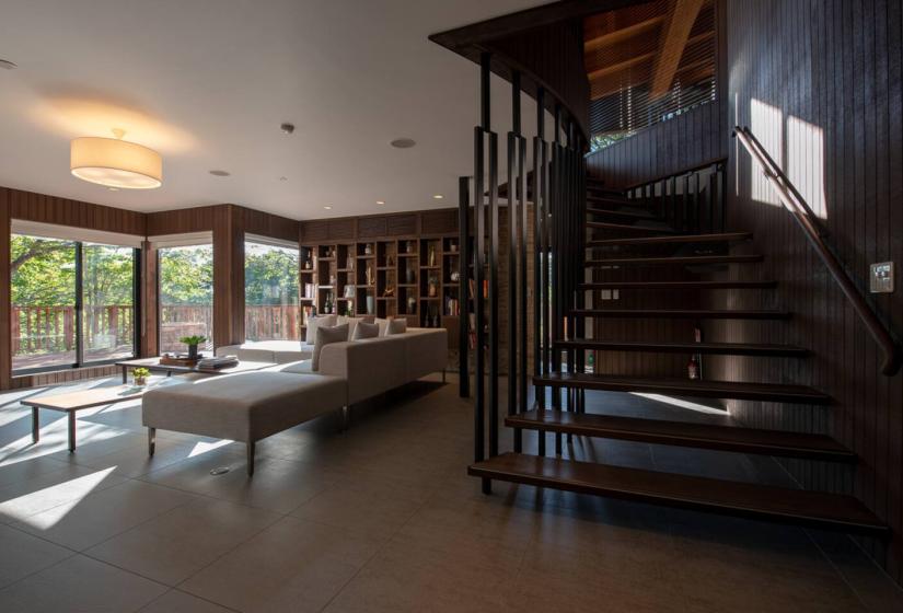 Stylish Annupuri Niseko chalet interior featuring elegant wooden staircase, white sofa and large windows with forest views