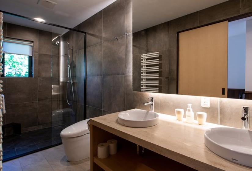 Contemporary ensuite bathroom in Chalet Kiraku featuring a walk-in glass shower, elegant vanity with vessel sink, heated towel rack, and modern fixtures, offering premium comfort for Niseko ski holiday guests.